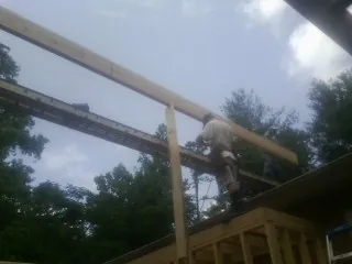 Carpenter setting a ridge beam over a new addition frame — Ice Dam Removal by Roofing Brothers in Broxton