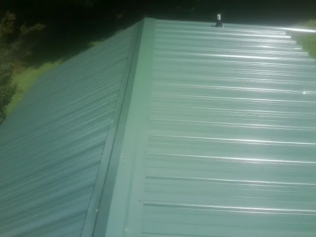 New green metal panels meeting at the ridge of a roof — Flat Roof Repair work by our crew in Broxton