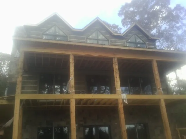 Dormers and porch framing on a large log home under construction — Roof Coating work by our crew in Broxton