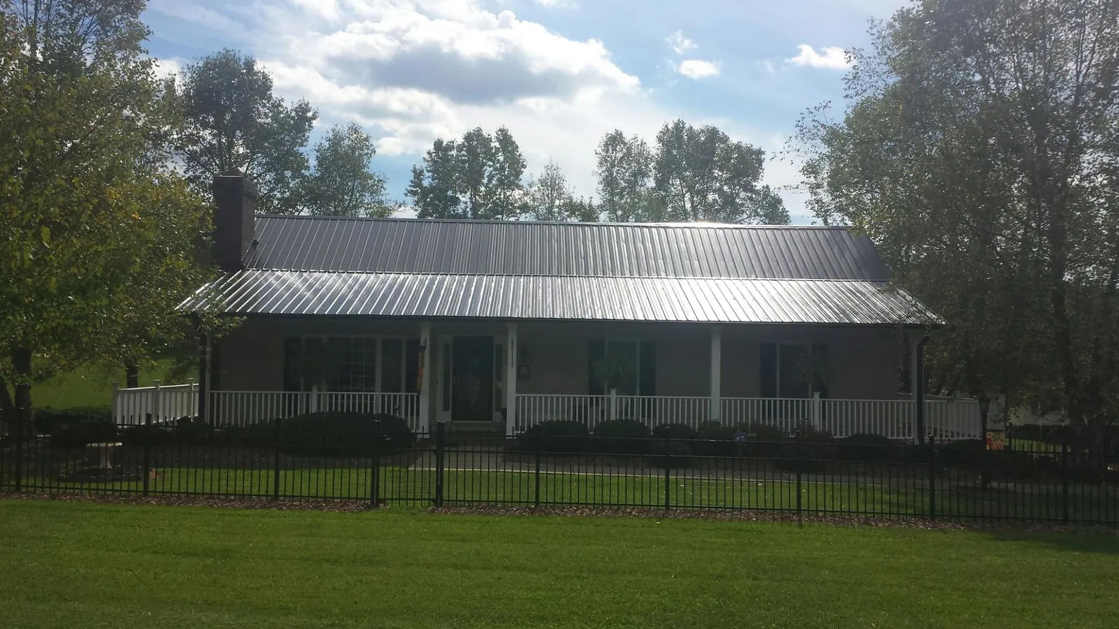 Gray metal roof on a brick ranch with a full width front porch — Gutter Guard Installation work by our crew in Broxton
